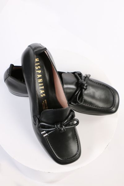 An elegant square toe moccasin made from a soft leather upper with a leather bow embellishment over the instep. Slip on and off with ease. Perfect for work, or for an elevated casual look. European sizing. Made in Spain. Leather upper, microfibre lining, 