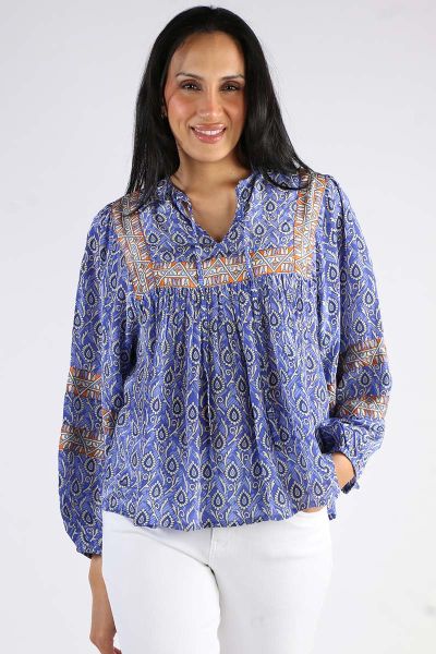 The Teel Blouse in Blue by Lollys Laundry is a beautiful and detailed blouse with a vibrant pattern in shades of blue, white, and orange, made from 100% viscose. It has a loose, airy fit, making it comfortable to wear all day long. The shirt is designed w