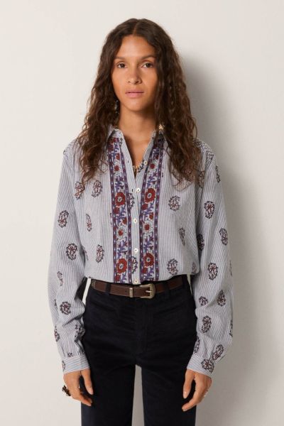 Soft cotton with a light hand forms the base of this blouse, striped in fine lines that carry subtle texture. Its relaxed fit feels effortless. The front placket is richly embroidered with panels in warm reds and indigos, while delicate gathers at the sho