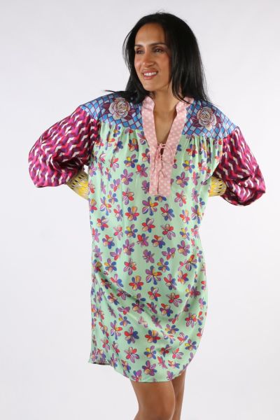 Tie placket long sleeve dress with wide cuffs in our Twisted Love print. Each piece of the dress is a different, colorful pattern. The packet is pink, with roses on both sides at the top. Sleeves are puffed in pink and purple zigzag stripes with wide yell