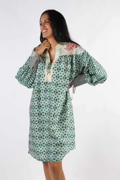 Tie placket long sleeve dress with wide cuffs in our Tropical Safari print. Each piece of the dress is a different, colorful pattern. The packet is pink, with roses on both sides at the top. Sleeves are puffed in pink and purple zigzag stripes with wide y
