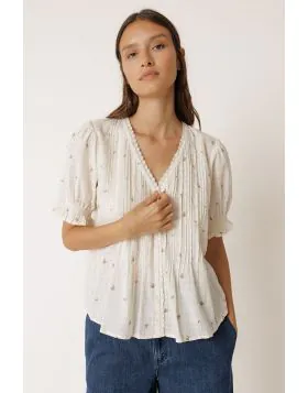 Rendered in a crisp ecru fabric with tiny floral motif throughout, this top features a gentle V neckline edged in delicate lace trim. Front pin tuck pleating adds soft texture through the bodice, while puff sleeves finished with smocked, elasticated ruffl