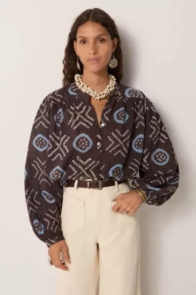 100% cotton voile blouse, cut loose with a soft drape, patterned in hand dyed geometrics. Circles framed in sky blue and dotted crosses run across a dark ground, the irregularity of each mark carrying the imperfect rhythm of craft. The voile is airy and t