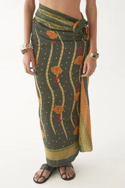 A canvas of deep tamarind green, where golden florals climb in rhythmic trails vintage batik, reimagined with an untamed spirit. Subtle red accents flicker through the print, like embers catching light, adding warmth and depth to its earthy elegance. More