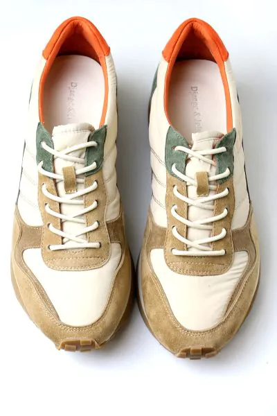 This style features a retro inspired low profile silhouette crafted with a mix of texturized fabrics, nylon, and suede panels. It stands out with a warm, earthy palette featuring neutral cream and khaki overlays, deep forest green accents, and a vibrant p