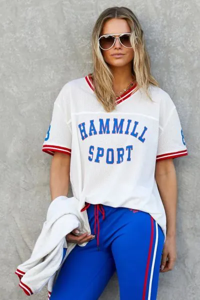New Hammill Sport mesh tee brings a classic athletic feel, featuring bold collegiate letters and contrast stripe trims that give it that vintage game day energy. Lightweight, breathable textured mesh with front Hammill Spot and 74 print on the back.
