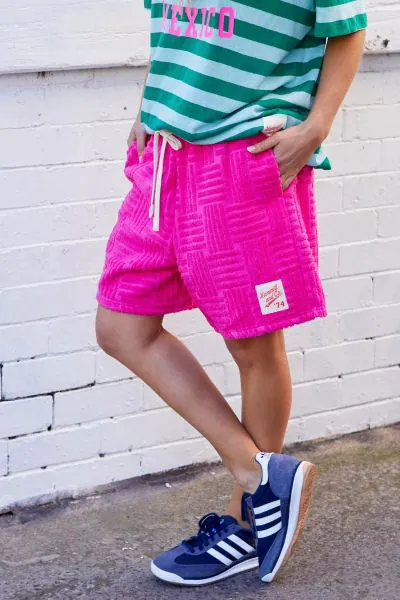 These shorts are pure chill vibes. Made from super soft pink towelling fabric, they have got a bold textured pattern that gives them a bit of edge. The relaxed fit, comfy elastic waistband, and drawstring tie make them perfect for throwing on after a swim