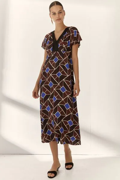 The Paz Torras Printed Dress features a V neck design and flutter sleeves, providing a balanced combination of comfort and style. Its full length cut offers extended coverage suitable for various settings, enhancing versatility in wardrobe options. Geomet