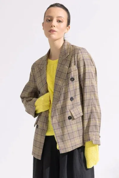 This refined look pairs a classic, structured check blazer with dark denim and a textured accessory for a polished yet approachable style. The Reese Blazer by Blacklist is a standout double-breasted piece featuring a timeless brown and tan check pattern. 