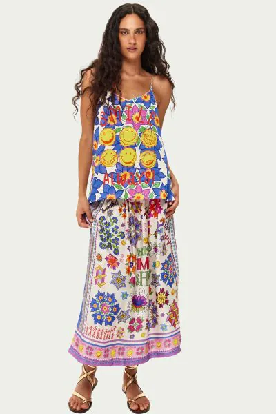 Vanessa midi skirt featuring bold This is ME SHOW lettering surrounded by printed flowers in blue, pink, purple, and orange. Sharp geometric cube patterns and yellow smiley faces scatter throughout, while decorative borders frame the hem. The flowing midi