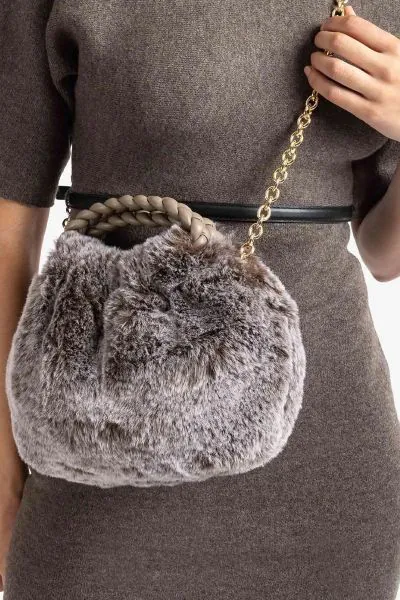 The UNISA ZBEN is a stylish faux fur clutch bag featuring a taupe colour blend. It offers versatility with a hand strap and a detachable chain, allowing it to be carried by hand or worn over the shoulder. Secured with a magnetic snap closure, this bag is 